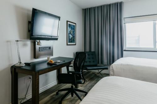 a hotel room with a desk and a tv at Riotel Matane in Matane