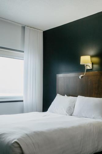 a bedroom with a white bed and a window at Riotel Matane in Matane