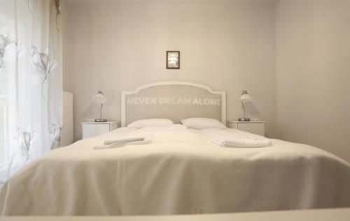 a white bedroom with a large bed with white sheets at Pastel Guesthouse in Balatonfüred
