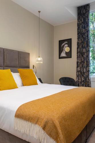 a bedroom with a large bed with yellow pillows at The Queen's Inn in Hawkhurst