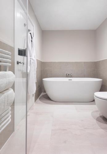 a white bathroom with a tub and a toilet at The Queen's Inn in Hawkhurst