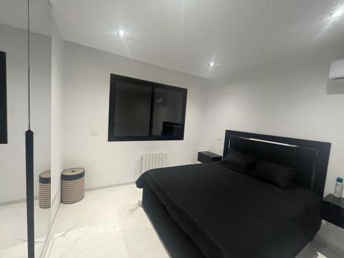 Tunis Résidence california في Le Kram: غرفة نوم بسرير أسود وتلفزيون بشاشة مسطحة