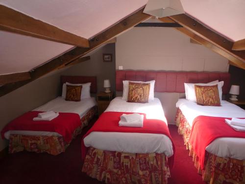um quarto com duas camas com lençóis vermelhos e brancos em The George Inn em Skipton