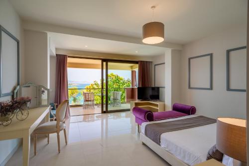 Schlafzimmer mit einem Bett, einem Schreibtisch und einem Balkon in der Unterkunft Balcony Boutique Hotel in Planos