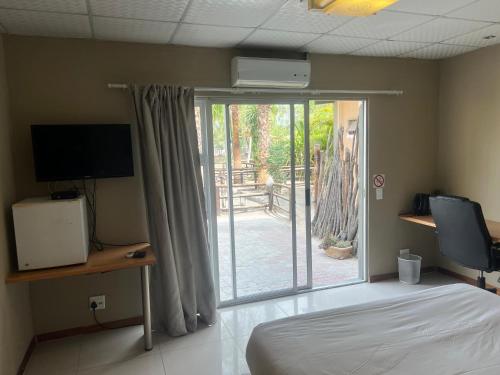 sypialnia z łóżkiem i przesuwnymi szklanymi drzwiami w obiekcie Ondangwa Rest Camp w Ondangwie