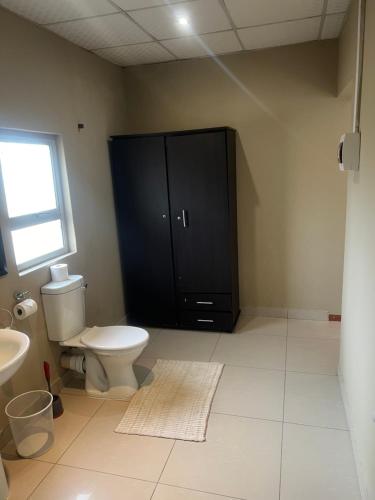 łazienka z toaletą i czarną szafką w obiekcie Ondangwa Rest Camp w Ondangwie