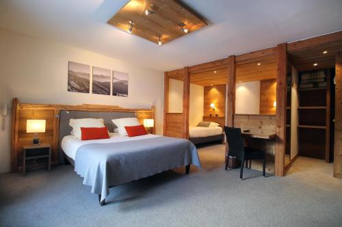 1 dormitorio con 1 cama, escritorio y 1 cama en Hôtel du Crêt Rond, en Valloire