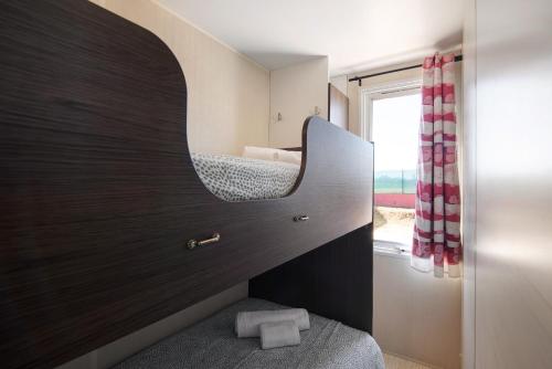 ein Bad mit einem Spiegel und ein Bett mit einem Fenster in der Unterkunft Mobile Home 2 - Olhão in Quelfes