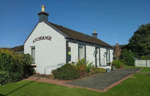 a white building with a sign on the side of it at Anchorage Guest House - Also 1 room available with Hot Tub in Balloch