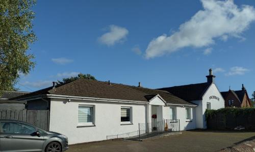 a white house with a car parked in front of it at Anchorage Guest House - Also 1 room available with Hot Tub in Balloch