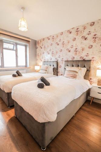 two beds in a bedroom with floral wallpaper at Spacious 1 bed flat-FREE Parking in New Bedfont