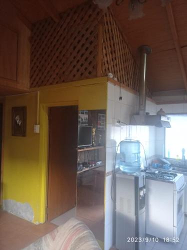 une cuisine avec un mur jaune et une cuisinière dans l'établissement Cabañas Nahuel, à Chile Chico