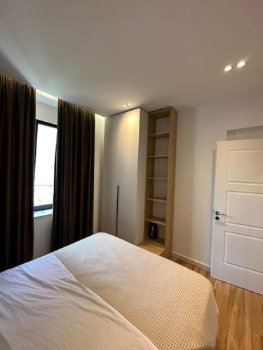um quarto com uma cama branca e uma janela em Sunrise Apartment em Tirana