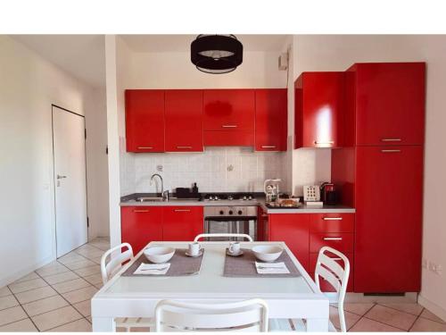 a kitchen with red cabinets and a white table and chairs at Olga & Giò - Vicino al Centro di Cesena in Cesena