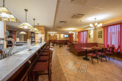 a restaurant with a bar and tables and chairs at Erzsébet Park Hotel in Parád