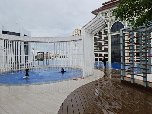 dos personas en una piscina en un edificio en Sakifa's Home @ Troika Kota Bharu, en Kota Bharu