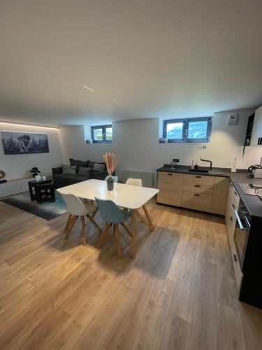 uma cozinha e sala de estar com uma mesa branca e cadeiras em Appartement - La Meute em Magland
