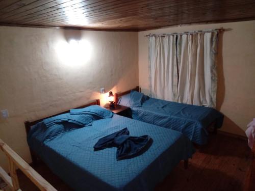 ein Schlafzimmer mit zwei Betten mit blauer Bettwäsche und einem Fenster in der Unterkunft CardónApart in Puerto Iguazú