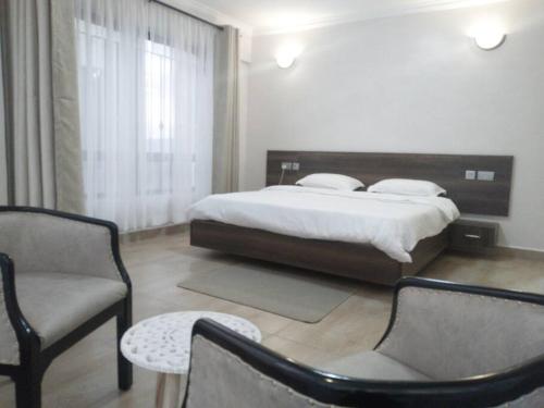 a bedroom with a bed and two chairs and a table at Bee Furnished apartments 3 in Nakuru