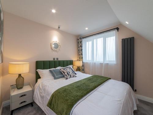 a bedroom with a bed with a green headboard and a window at Pass the Keys FLAT 3 Modern and Luxurious Duplex 3Br Central Location in London