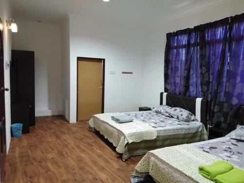 a bedroom with two beds and a door with curtains at Alin Roomstay Dungun in Dungun