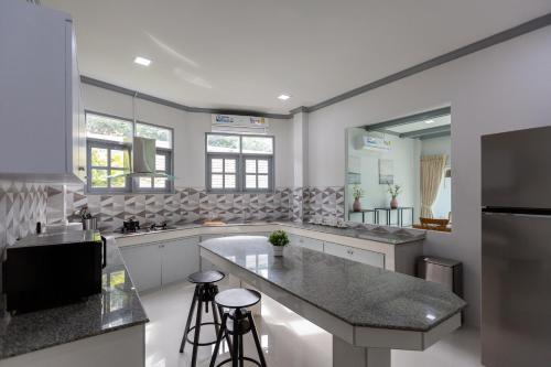 a kitchen with a large island with two bar stools at Houses of Sunny in Bang Sare