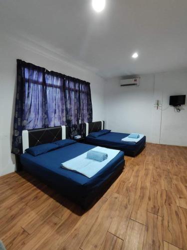 two beds in a room with a wooden floor at Alin Roomstay Dungun in Dungun