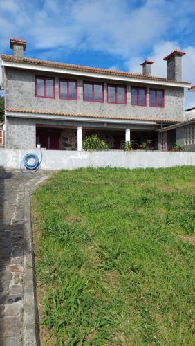 a house with red windows and a green yard at SERRADO Da EIRA in Lajes das Flores