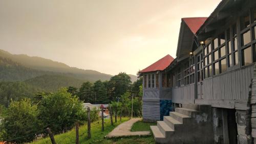 a building with a staircase next to a mountain at Black Bear Cottage khajjiar in Khajjiar 