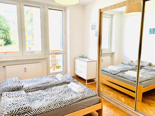 two beds in a room with a mirror at Apartament SŁONECZNY in Bydgoszcz