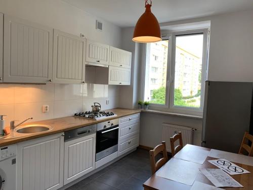 a kitchen with white cabinets and a table and a window at Apartament SŁONECZNY in Bydgoszcz