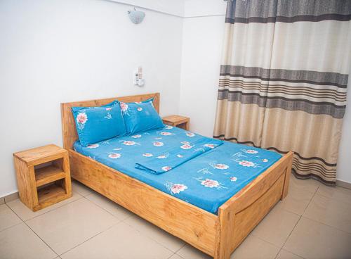 a small bedroom with a wooden bed with blue sheets at Magnifique Maison de ville Bord de mer Cotonou Fidrjossè in Cotonou