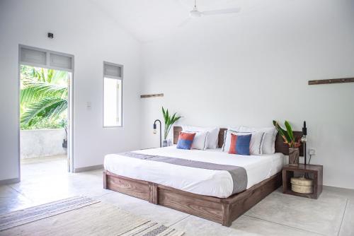 a bedroom with a large bed with white walls at GOOD STORY at NIRBANA ISLAND in Ahangama