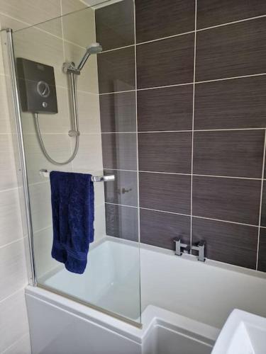 ein Bad mit einer Dusche und einem blauen Handtuch in der Unterkunft Home in Melton Mowbray in Melton Mowbray