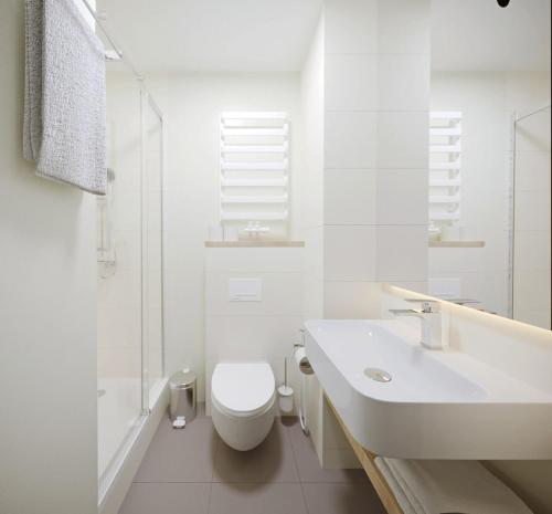 a white bathroom with a toilet and a sink at Drevny Grad Park-hotel in Lviv