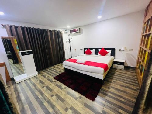 ein Schlafzimmer mit einem großen Bett mit roten Kissen in der Unterkunft PuHoR Hotel Plaza Inn in Guwahati