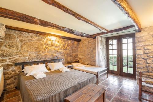 ヴィエイラ・ド・ミーニョにあるUveiras Villa Gardenの石壁のベッドルーム1室(ベッド2台付)
