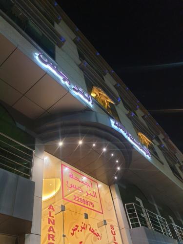 una señal en el lateral de un edificio por la noche en أجنحة النرجس أبها, en Abha