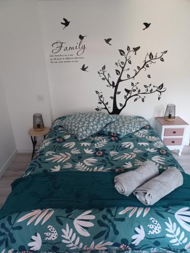 ein Schlafzimmer mit einem Bett mit einem Baum an der Wand in der Unterkunft Duplex cosy et douillet in Ernée