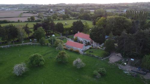 an aerial view of a house on a green field at Gîte de la Ferme du Clos Giot in Saint-Vaast-la-Hougue