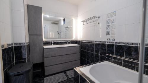 een badkamer met een wastafel, een bad en een spiegel bij Big 5-bedroom house in Capelle aan den IJssel in Capelle aan den IJssel