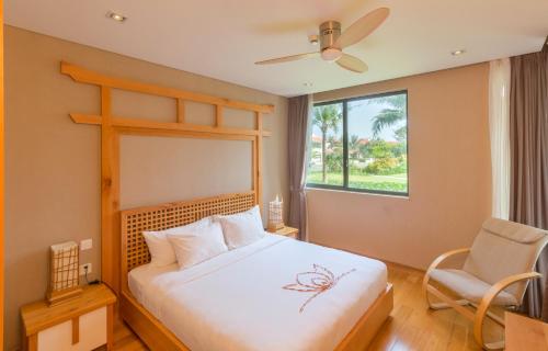 een slaapkamer met een bed, een stoel en een raam bij Maha Mangala Zen Garden & Residence in Da Nang