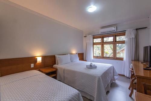 a hotel room with two beds and a window at Pousada Villa Verde in Canela