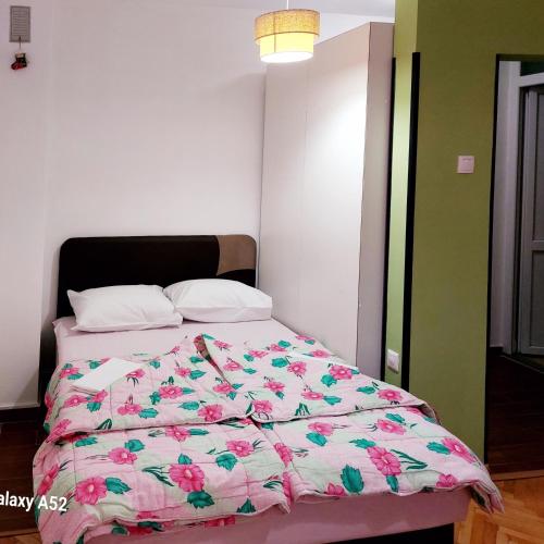 a bedroom with a bed with a pink floral comforter at Apartman PAVLE in Pluzine
