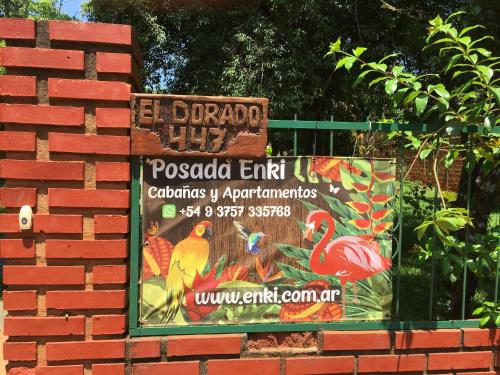 ein Schild an einer Backsteinmauer mit einem Schild für ein Restaurant in der Unterkunft Posada Enki in Puerto Iguazú