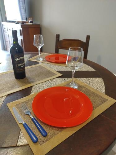Una mesa con un plato naranja y una botella de vino. en Montaña Sol Malbec, en Ciudad Lujan de Cuyo