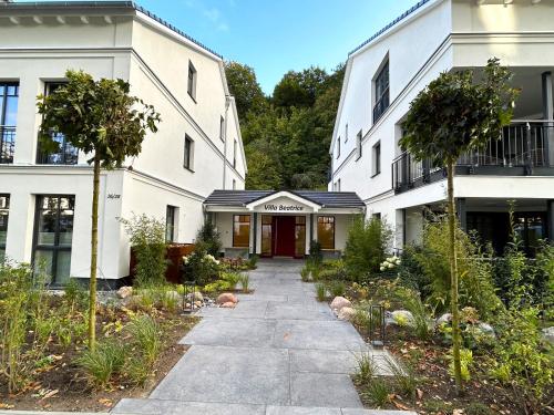 a walkway in front of two white buildings at Villa Beatrice - WE 13 mit eigener Sauna, 2 Dachterrassen, kleiner Meerblick in Binz