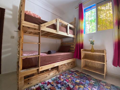 - une chambre avec 2 lits superposés et un tapis coloré dans l'établissement Red Carpet Surf Camp, à Tamraght Ouzdar