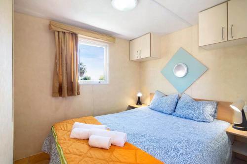 a bedroom with a blue bed with blue pillows and a window at Mobile Home 1 - Olhão in Quelfes