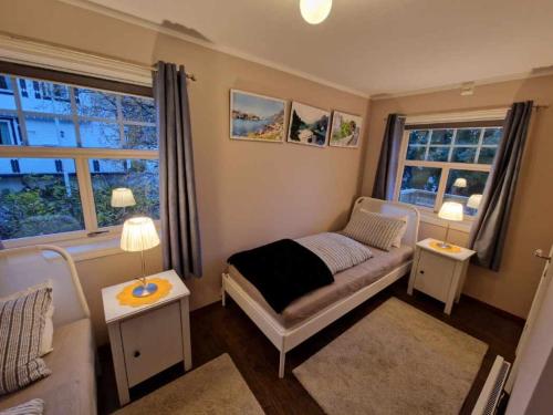 a small bedroom with a bed and two windows at Dragon Villa Reine in Reine